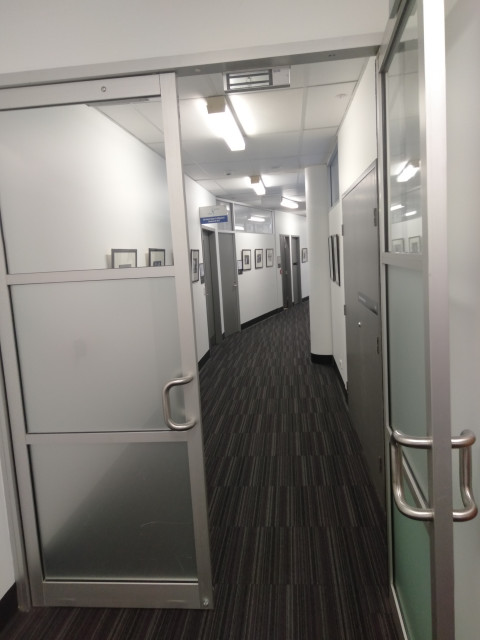 Hallway containing offices behind glass door