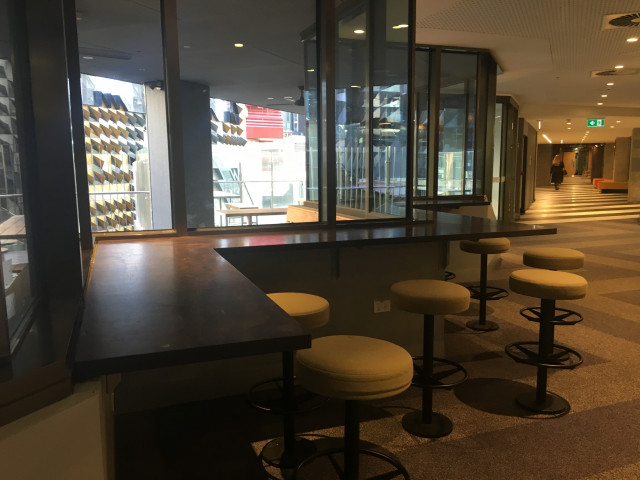 The zig zag seating is beside the door to go to the outdoor study space, beside the door to the stairs and the elevators.