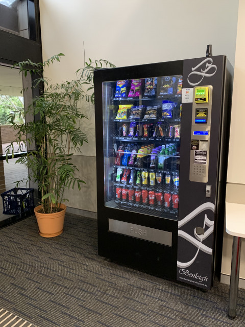 View of vending machine, located directly left of main entrance to building 38, in corner on left hand side of foyer area